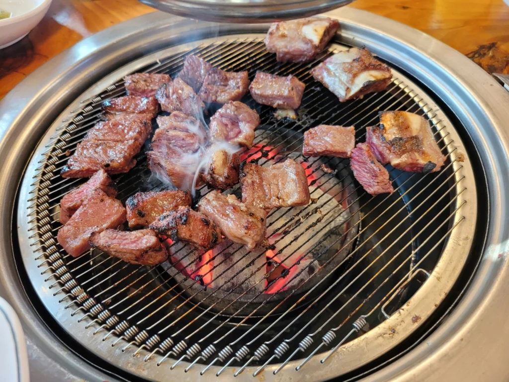 갈비를 숯불 불판위에 굽고 연기가 피어오르는 사진